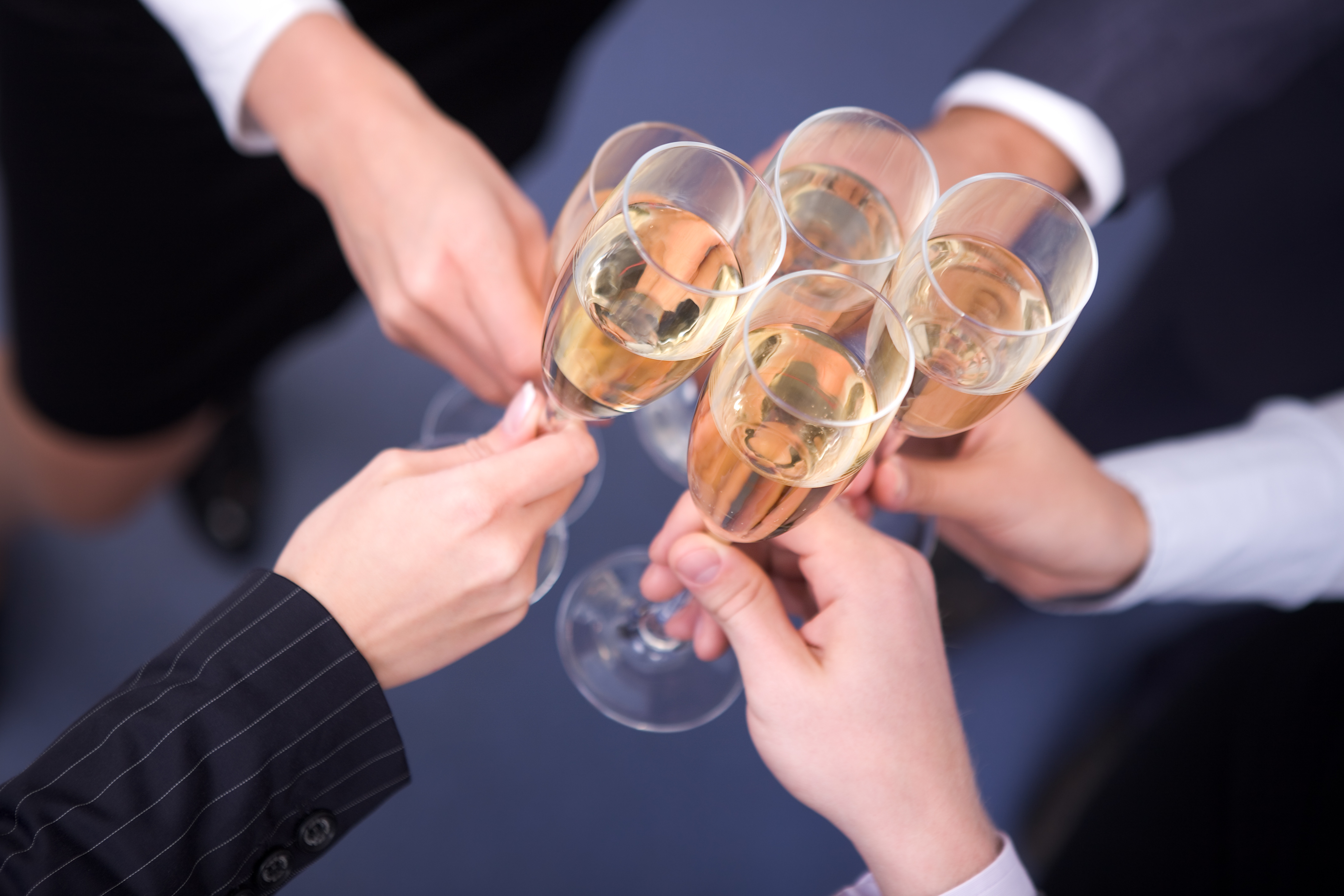 Close-up of human hands cheering up with flutes of golden champagne